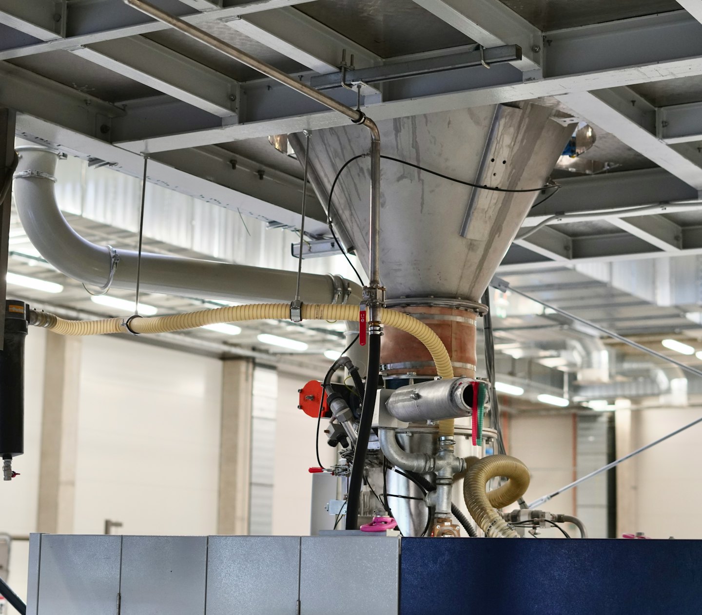 Przemysłowy metalowy zasobnik i system rurociągów w zakładzie produkcyjnym.