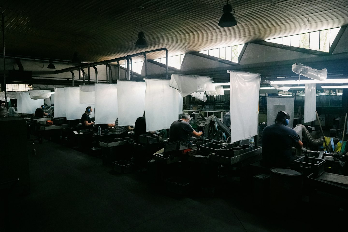 Męscy pracownicy fabryki obsługujący maszyny w ruchliwym warsztacie.